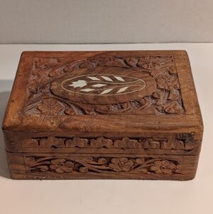 A hand-carved wooden trinket or jewelry box, typically made of sheesham wood.